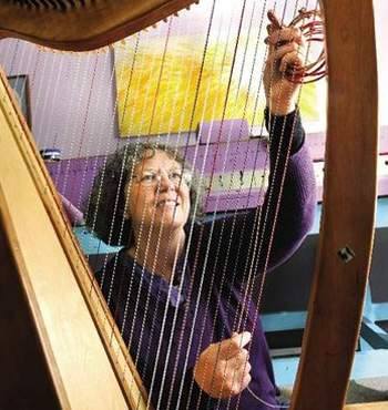 Laurie Nielsen, owner of Markwood Heavenly Strings & Cases, restringing a harp, replacing harp strings with Markwood custom harp strings